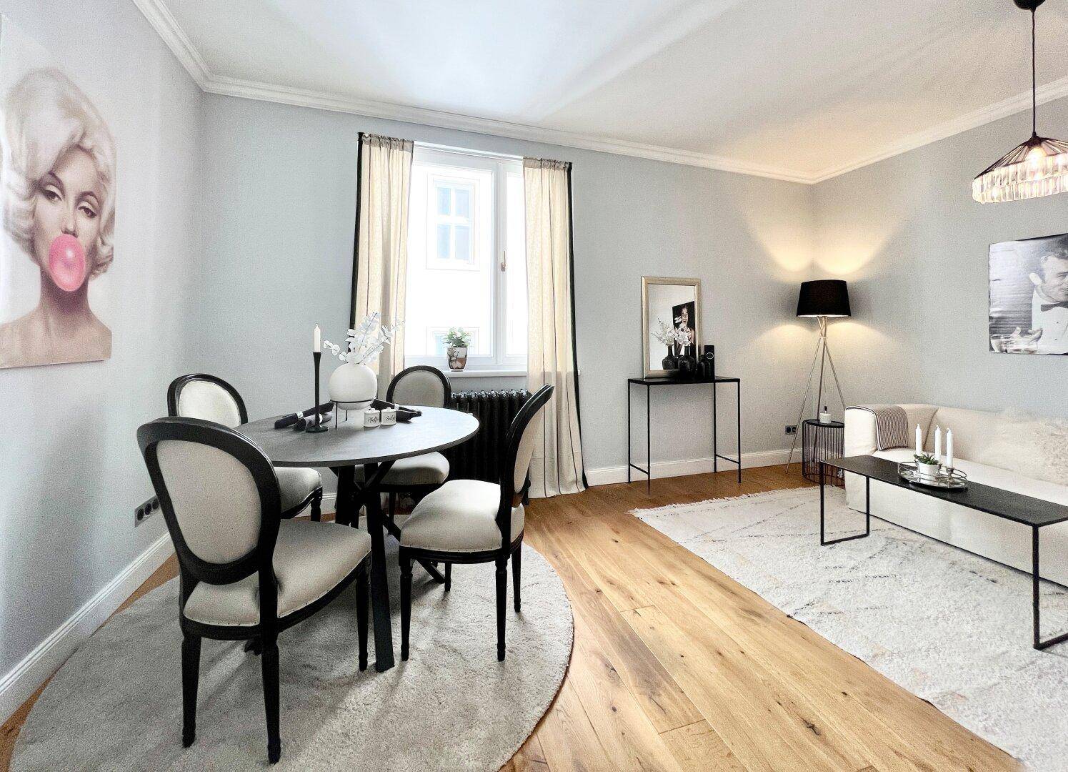Stilvoller Wohn- und Essbereich mit Holzboden, eleganten Möbeln und dekorativen Bildern.
