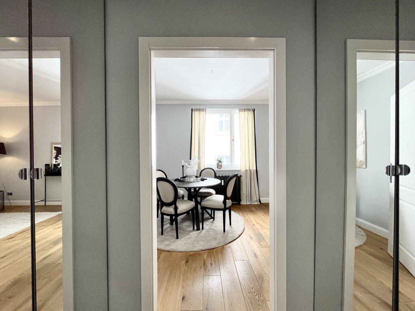 Blick durch den Türrahmen in das helle Wohn- und Esszimmer mit Parkettboden.