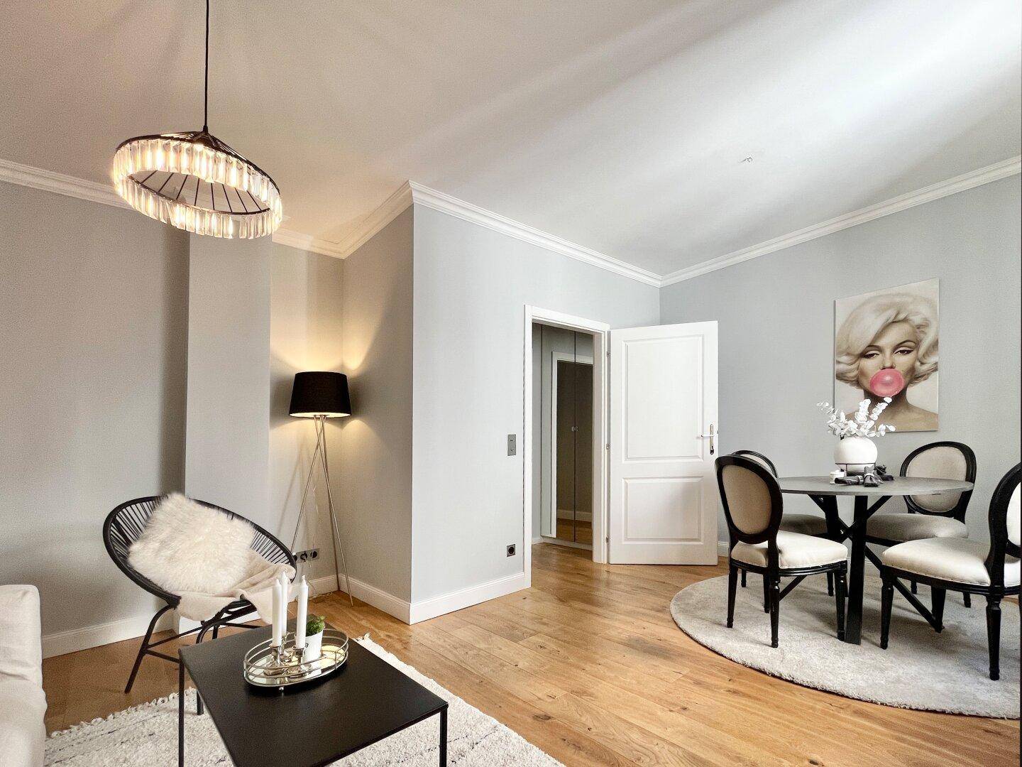 Helles Wohn- und Esszimmer mit Parkettboden, moderner Einrichtung und dekorativen Elementen.