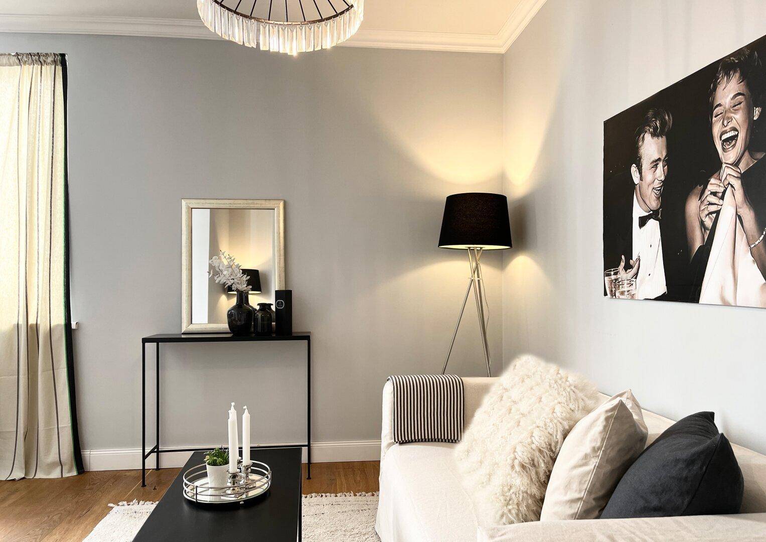 Gemütlicher Wohnbereich mit Sofa, Stehlampe und dekorativen Bildern an der Wand.