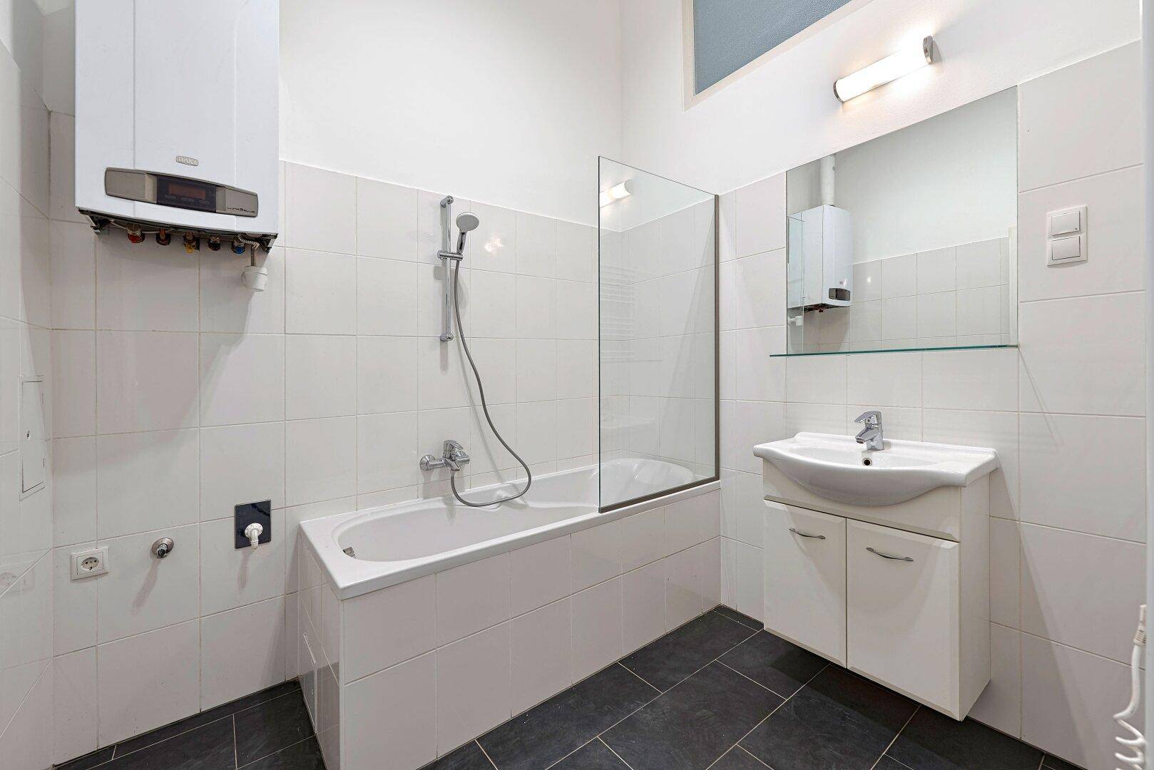 Modernes Badezimmer mit Badewanne, Duschabtrennung und Gastherme an der Wand.