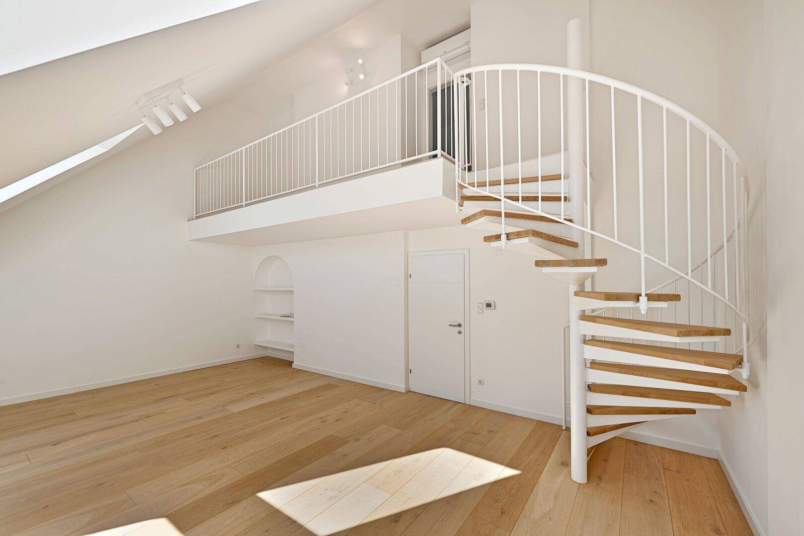 Geräumiger Wohnbereich mit offener Galerie, Wendeltreppe und hellem Holzfußboden.