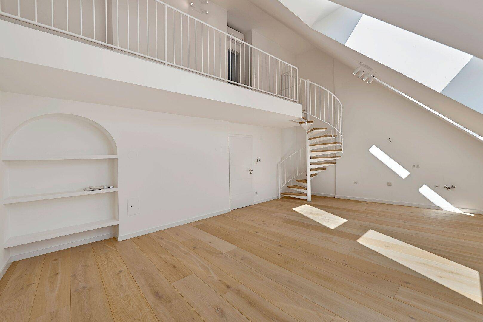 Heller Wohnraum mit integrierten Regalen, Wendeltreppe zur Galerie und Holzfußboden.