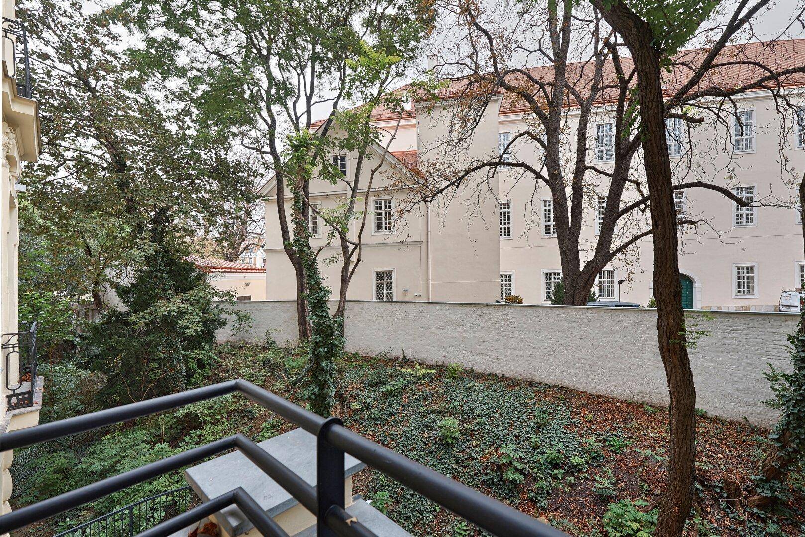 Weiterer Blick vom Balkon in den ruhigen, grünen Innenhof mit altem Baumbestand.