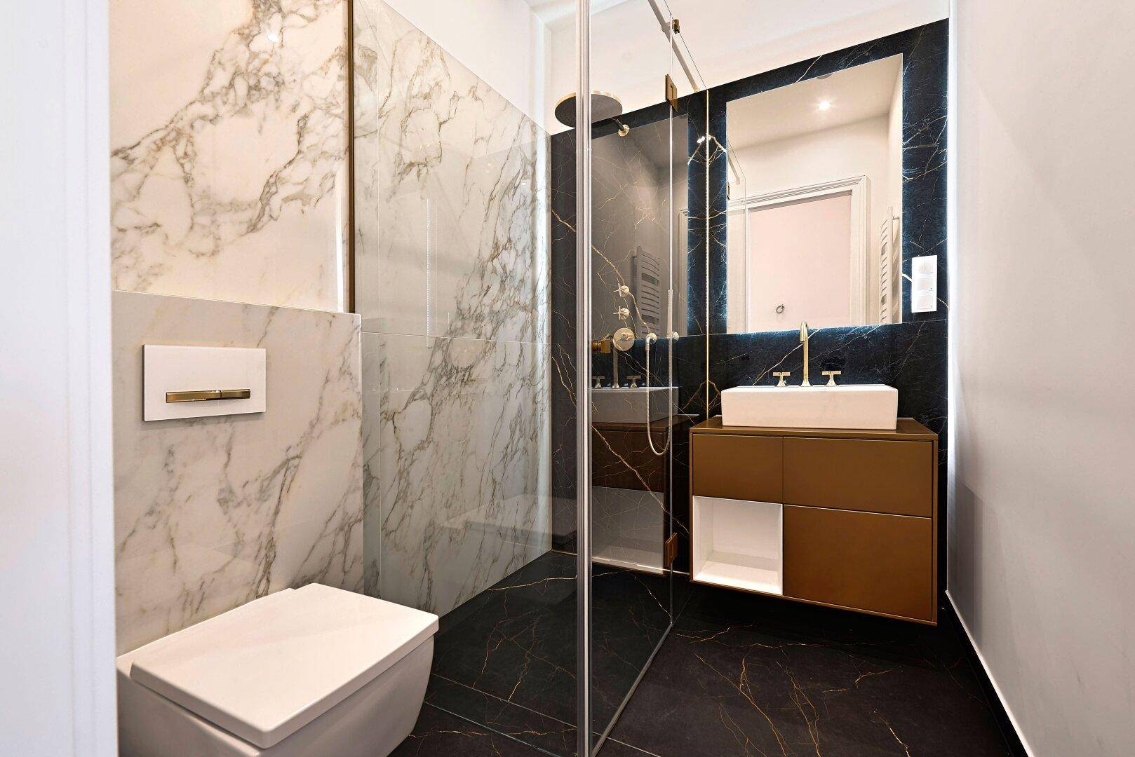 Modernes Gäste-WC mit eleganten Marmorfliesen, wandhängender Toilette und goldenen Armaturen.