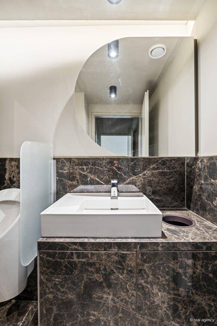 Nahaufnahme eines modernen Waschbeckens mit Armatur und einem stilvollen Spiegel in einem Gäste-WC.