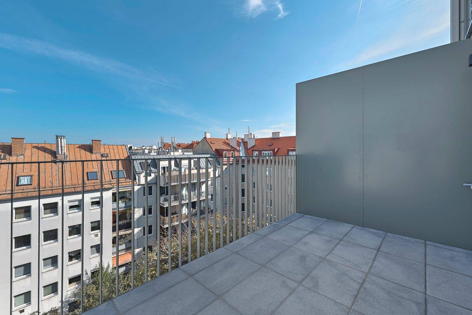 Moderner Balkon mit Fliesenboden und Blick auf die umliegenden Gebäude der Stadt.