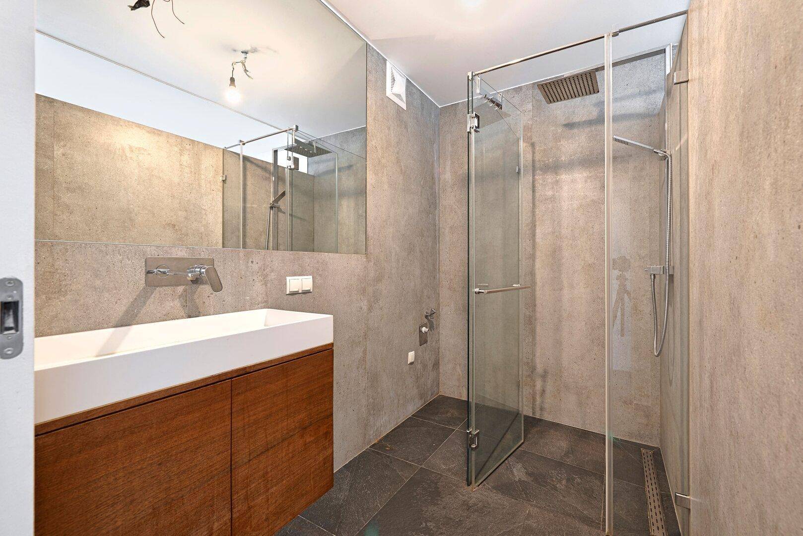 Modernes Badezimmer mit großem Waschtisch, Spiegel und geräumiger begehbarer Dusche.