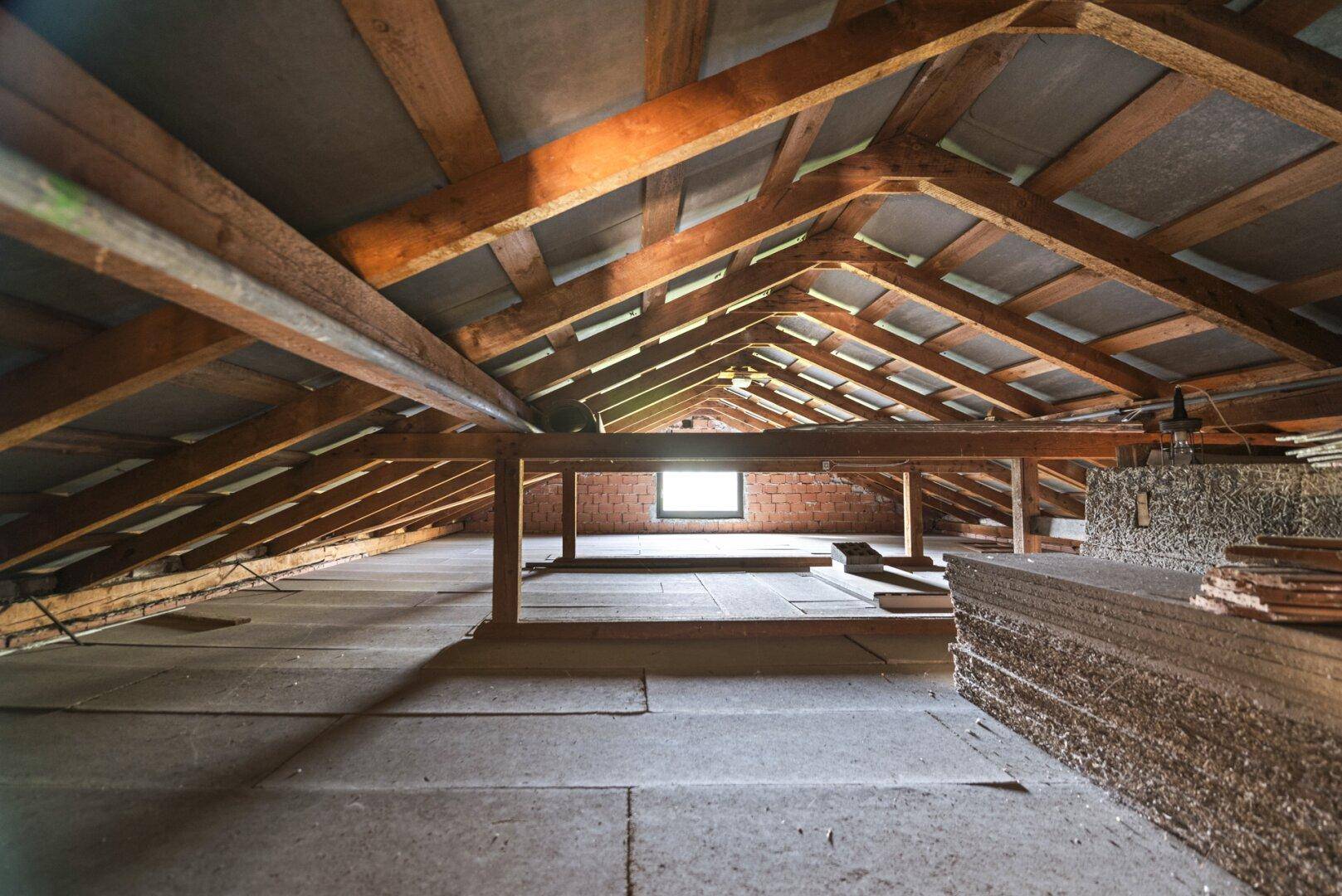 Unausgebauter Dachboden mit sichtbarer Holzkonstruktion und Tageslichtfenster.