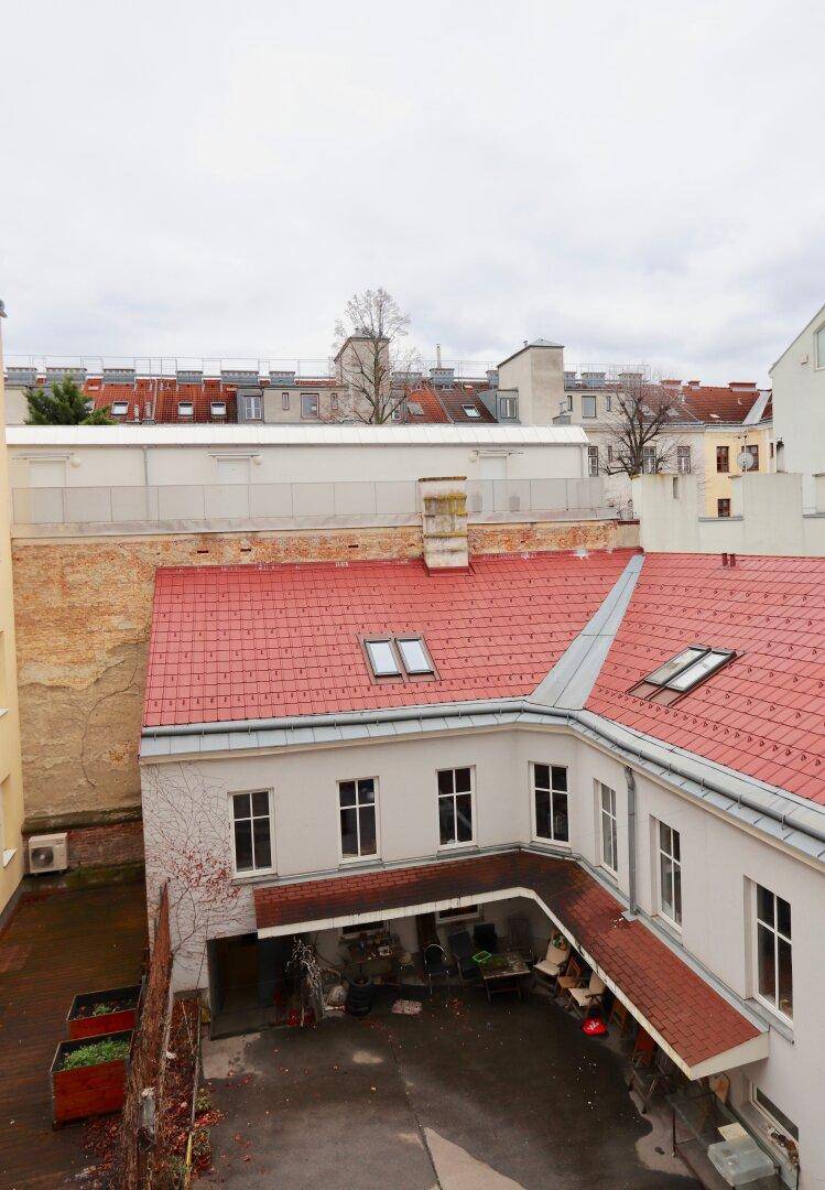 Dachaufsicht auf einen Innenhof mit roten Ziegeldächern, Dachfenstern und umliegenden Gebäuden.