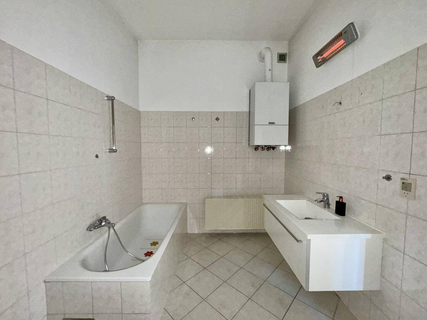 Helles Badezimmer mit Badewanne, modernem Waschbecken und Wandheizung, alles in gutem Zustand.