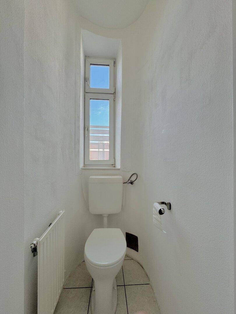 Kleines separates WC mit Fenster, Toilette und Heizkörper, funktional und hell.
