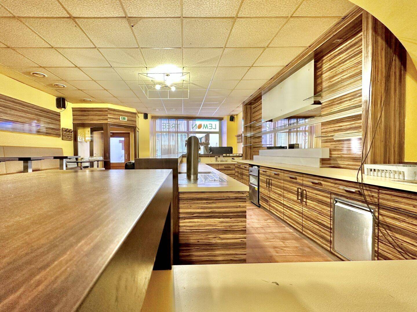 Detailansicht der Bar mit Zapfanlage, Holzschränken und integrierten Kühlgeräten, bereit für den Service.