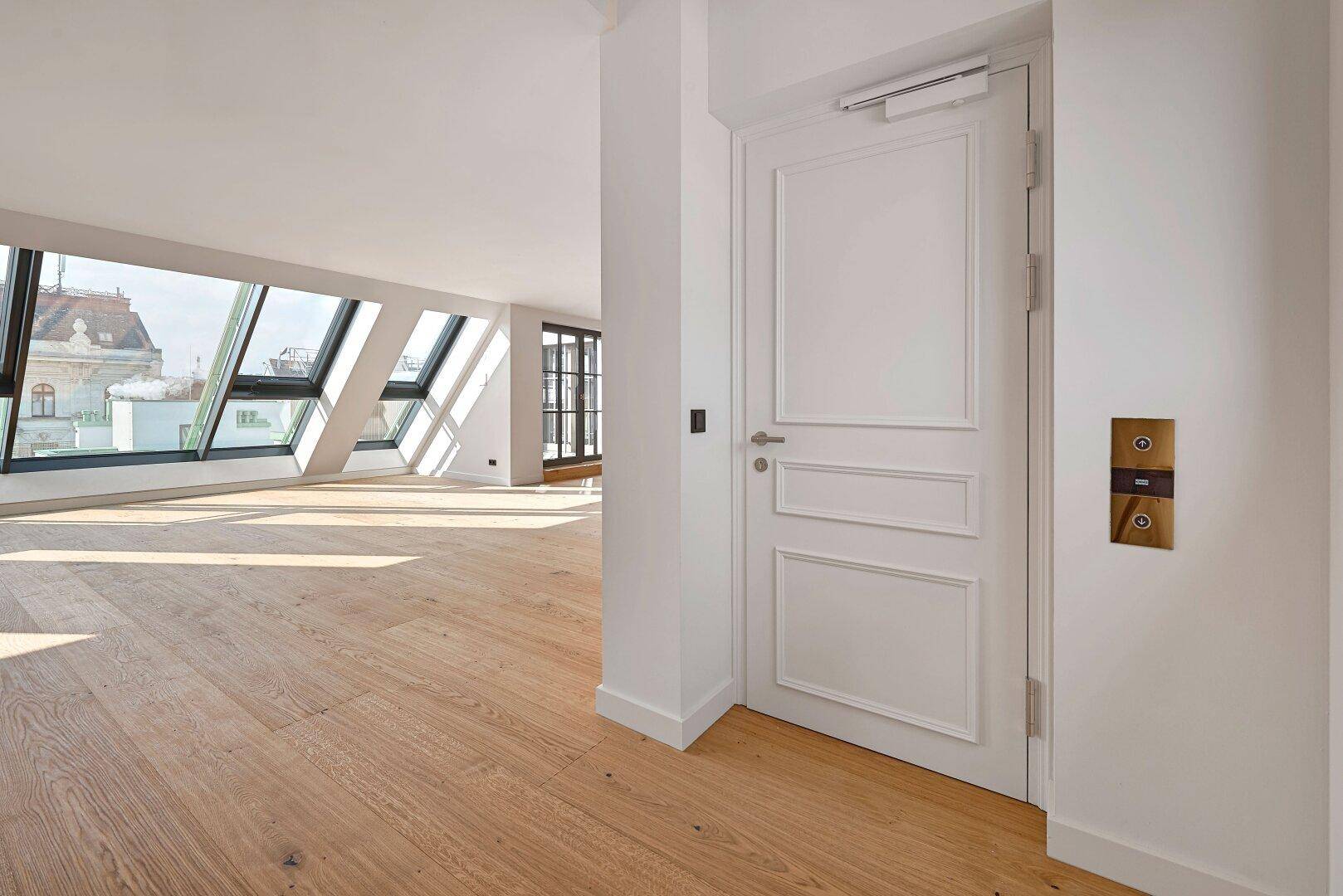 Heller Eingangsbereich mit Holzboden und einer modernen Tür, die zu den Wohnräumen führt.