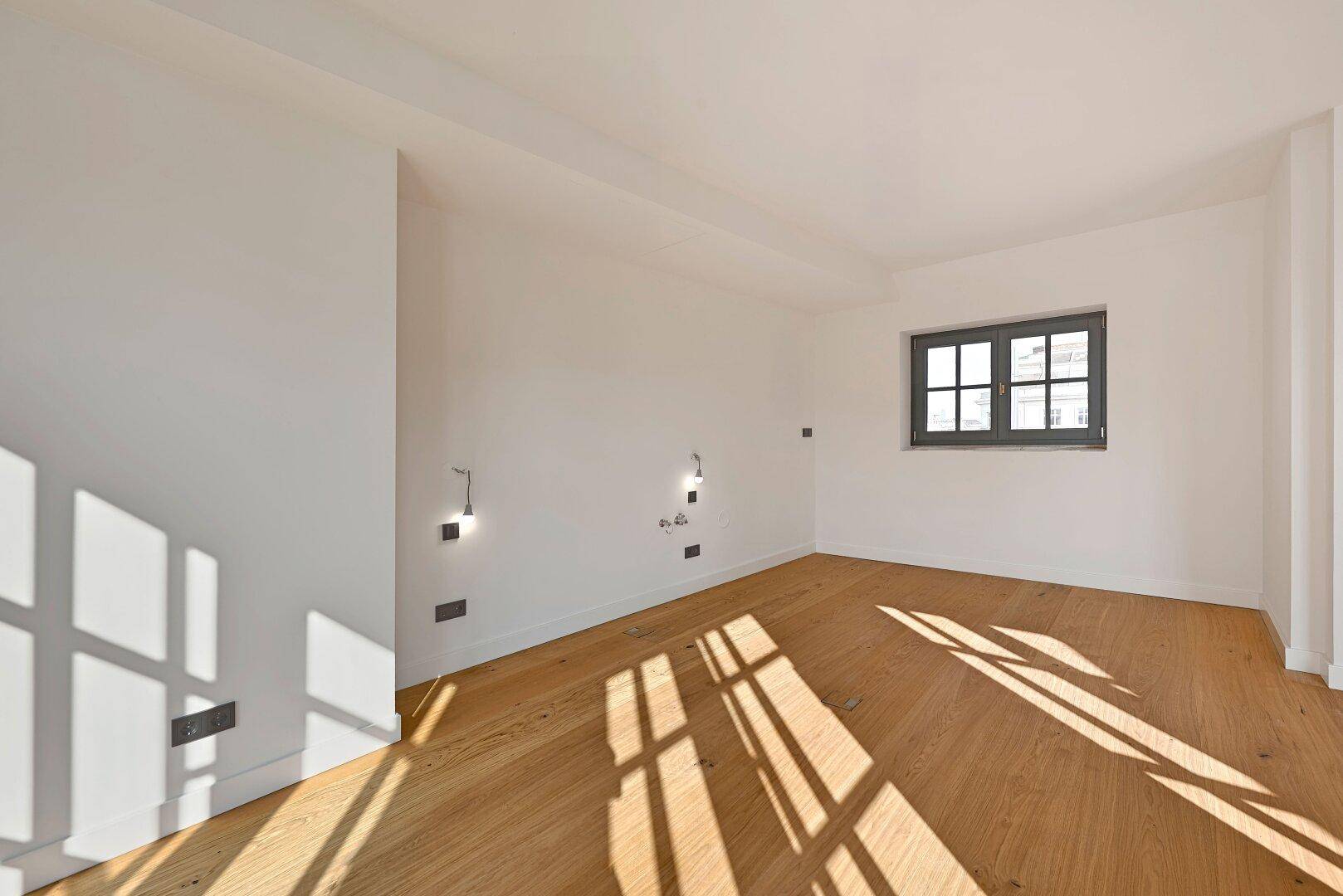 Heller, leerer Raum mit Holzboden und einem Fenster, bereit für individuelle Gestaltung.