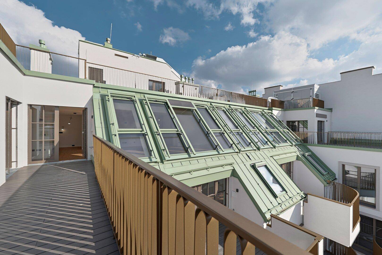 Dachterrasse mit Blick auf die umliegenden Gebäude und die grüne Dachkonstruktion.
