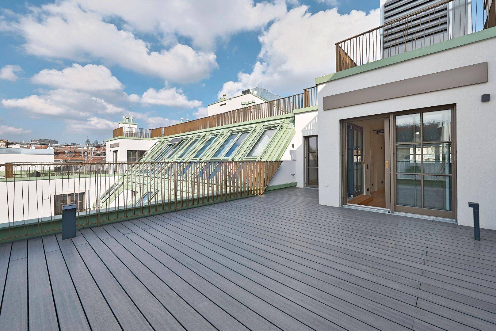 Geräumige Dachterrasse mit Holzdielen und Blick auf die Stadt, ideal für Outdoor-Aktivitäten.