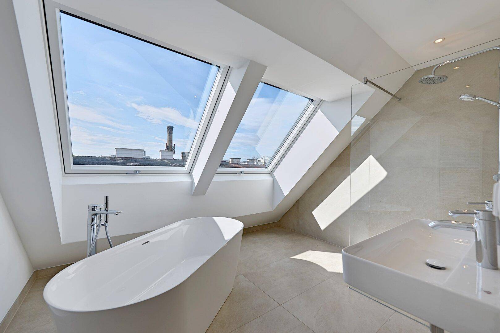 Modernes Badezimmer im Dachgeschoss mit freistehender Badewanne, Dusche und großen Dachfenstern.