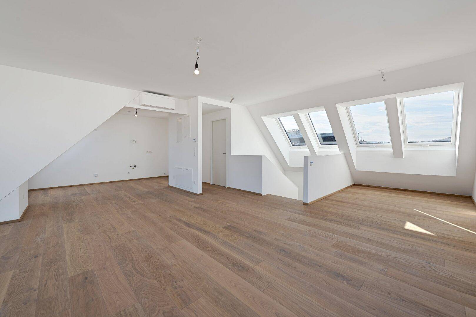 Geräumiger Wohnbereich mit Holzboden, Dachfenstern und Klimaanlage, ideal für offenes Wohnen.