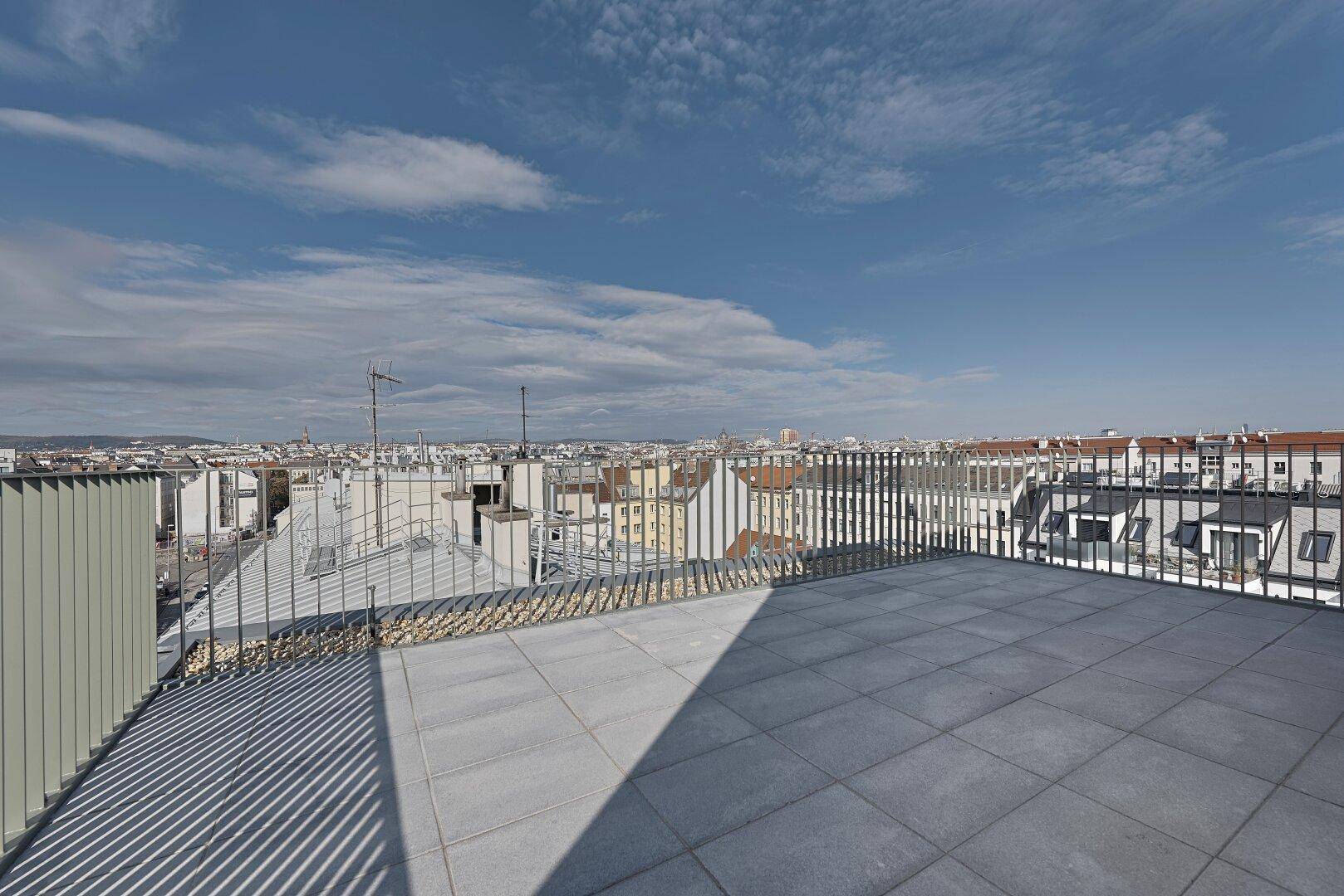 Weitläufige Dachterrasse mit Fliesenboden und Panoramablick über die Stadt.