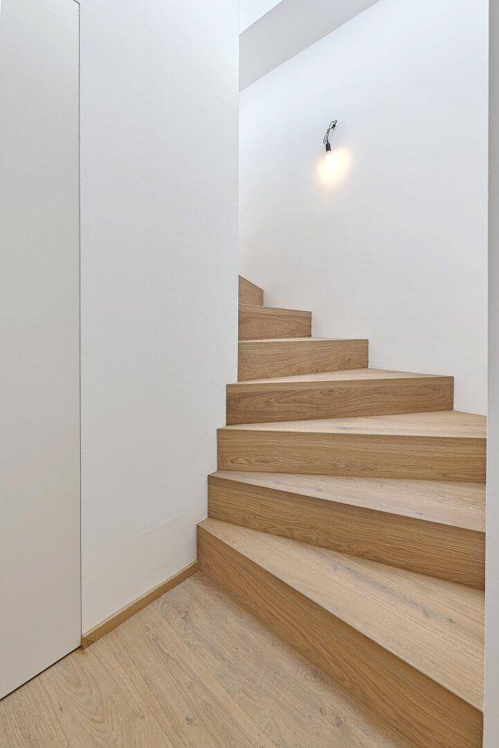 Moderne Holztreppe mit minimalistischem Design, die die verschiedenen Ebenen der Wohnung verbindet.