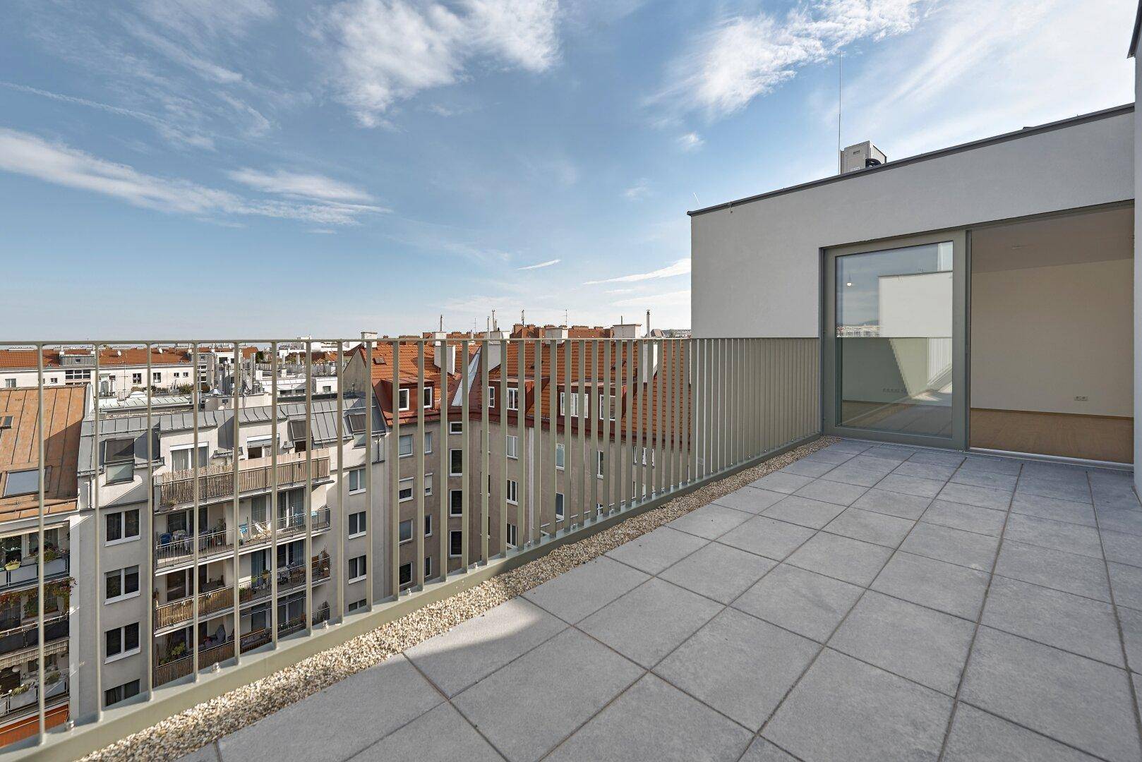 Weitläufige Dachterrasse mit Fliesenboden und modernem Geländer, bietet einen weiten Stadtblick.