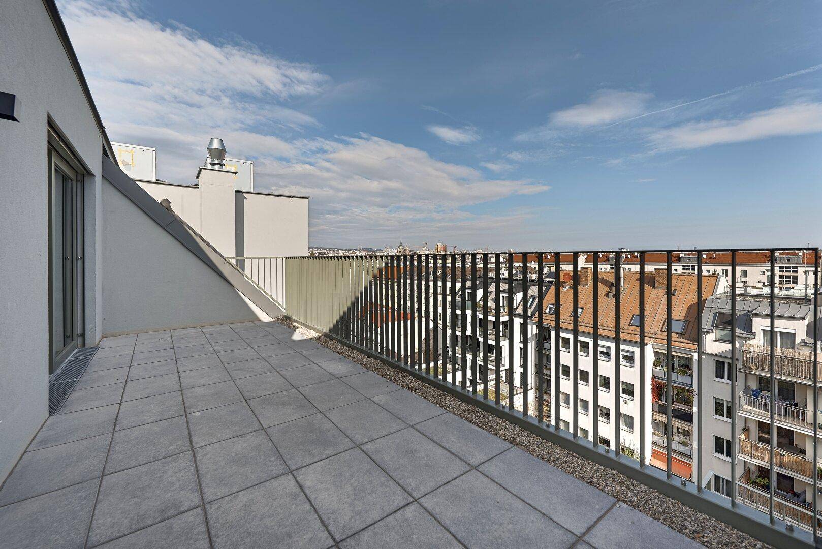 Große, geflieste Dachterrasse mit Panoramablick über die Dächer der Stadt und viel Freiraum.