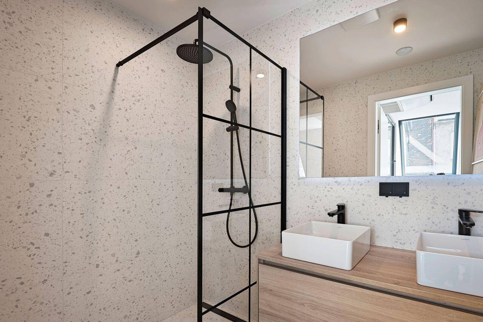 Modernes Badezimmer mit begehbarer Dusche, Doppelwaschbecken und Terrazzo-Fliesen in hellem Design.