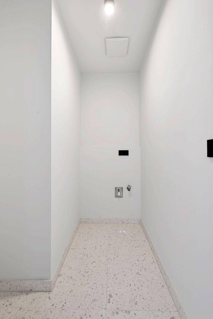 Praktischer Hauswirtschaftsraum mit Fliesenboden und Anschlüssen für Waschmaschine und Trockner.