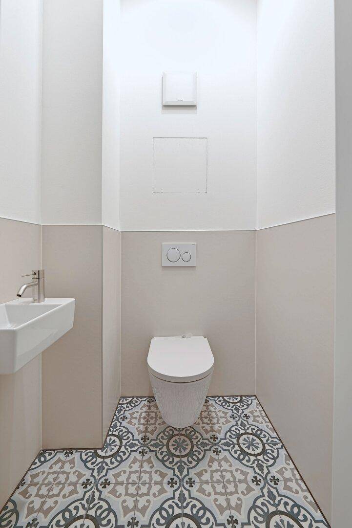 Modernes Gäste-WC mit auffälligen gemusterten Fliesen und wandhängendem WC.