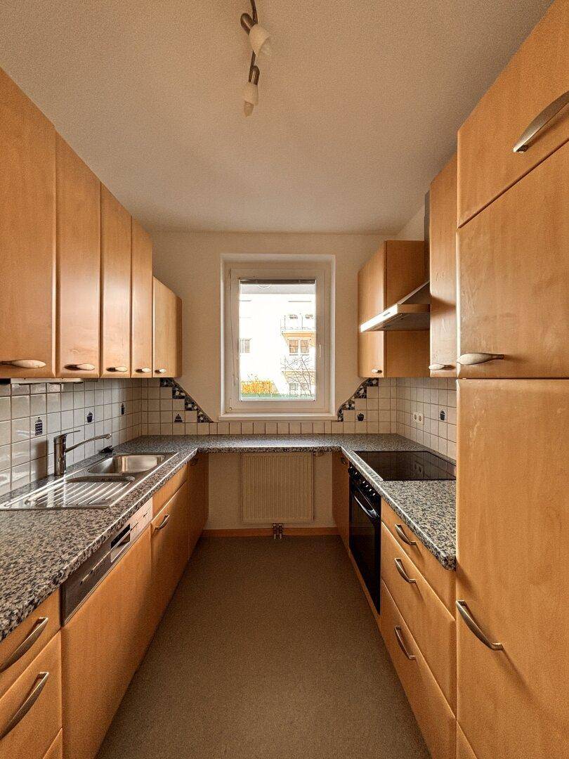 Funktionale Küche mit U-förmiger Anordnung, Holzschränken und Granitarbeitsplatten.