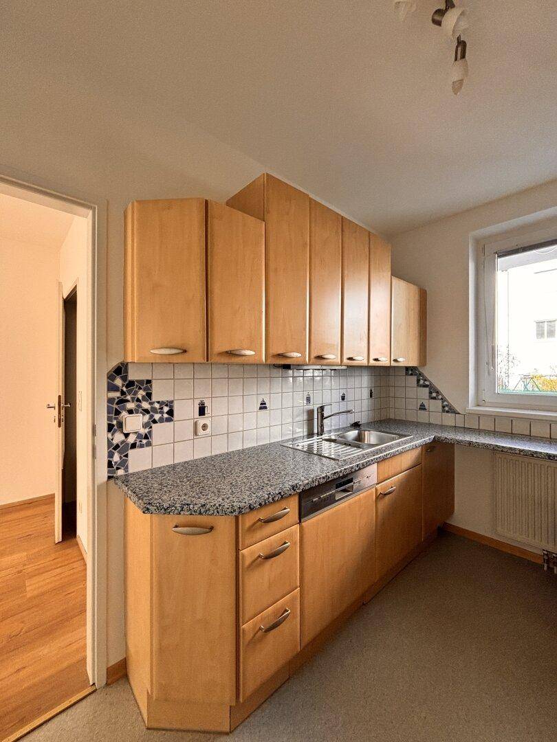 Helle Küche mit Holzschränken, Granitarbeitsplatte und gefliestem Spritzschutz.