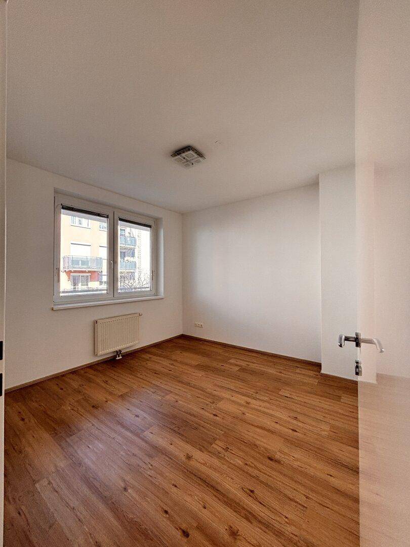 Helles Zimmer mit Holzboden und Fenster, bietet eine angenehme Wohnatmosphäre.