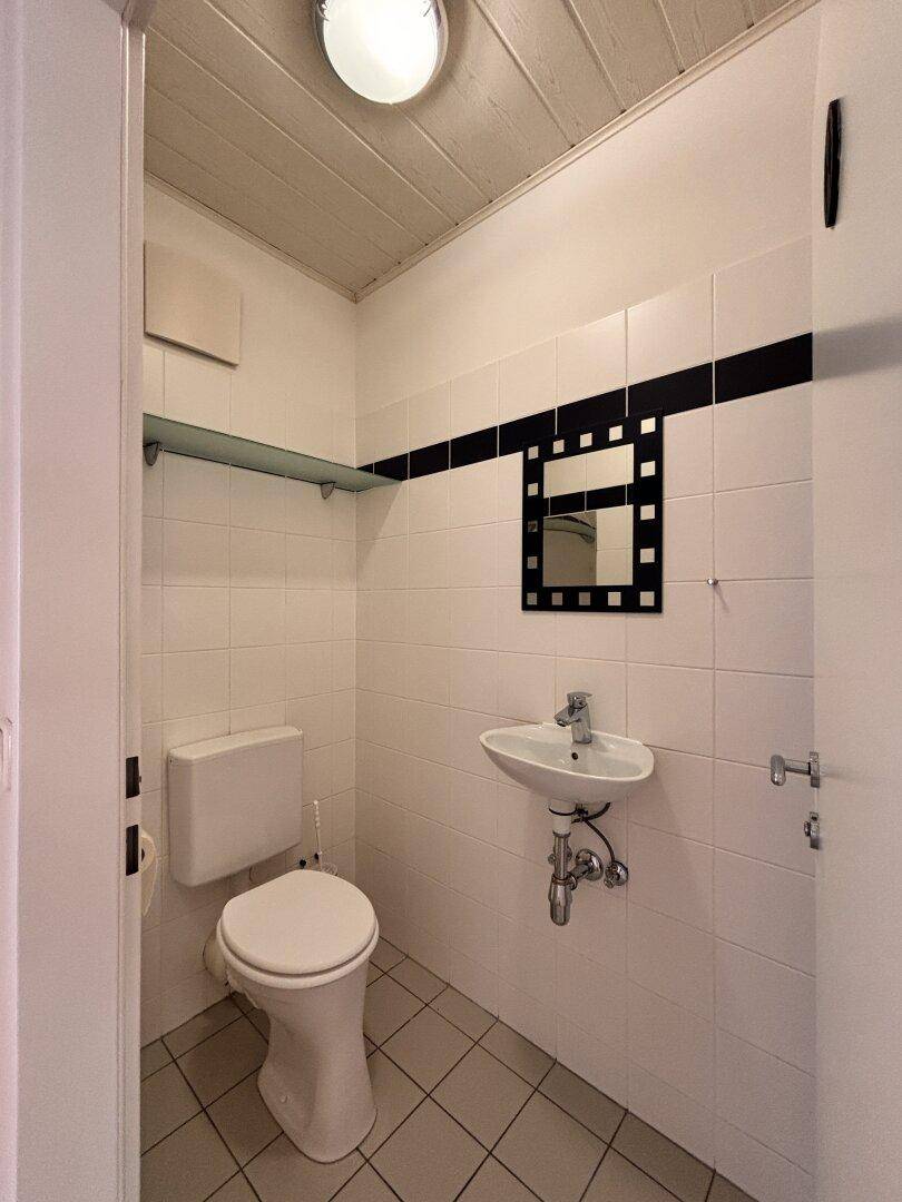 Kleines Gäste-WC mit Toilette, Handwaschbecken und weiß-schwarzen Fliesen.