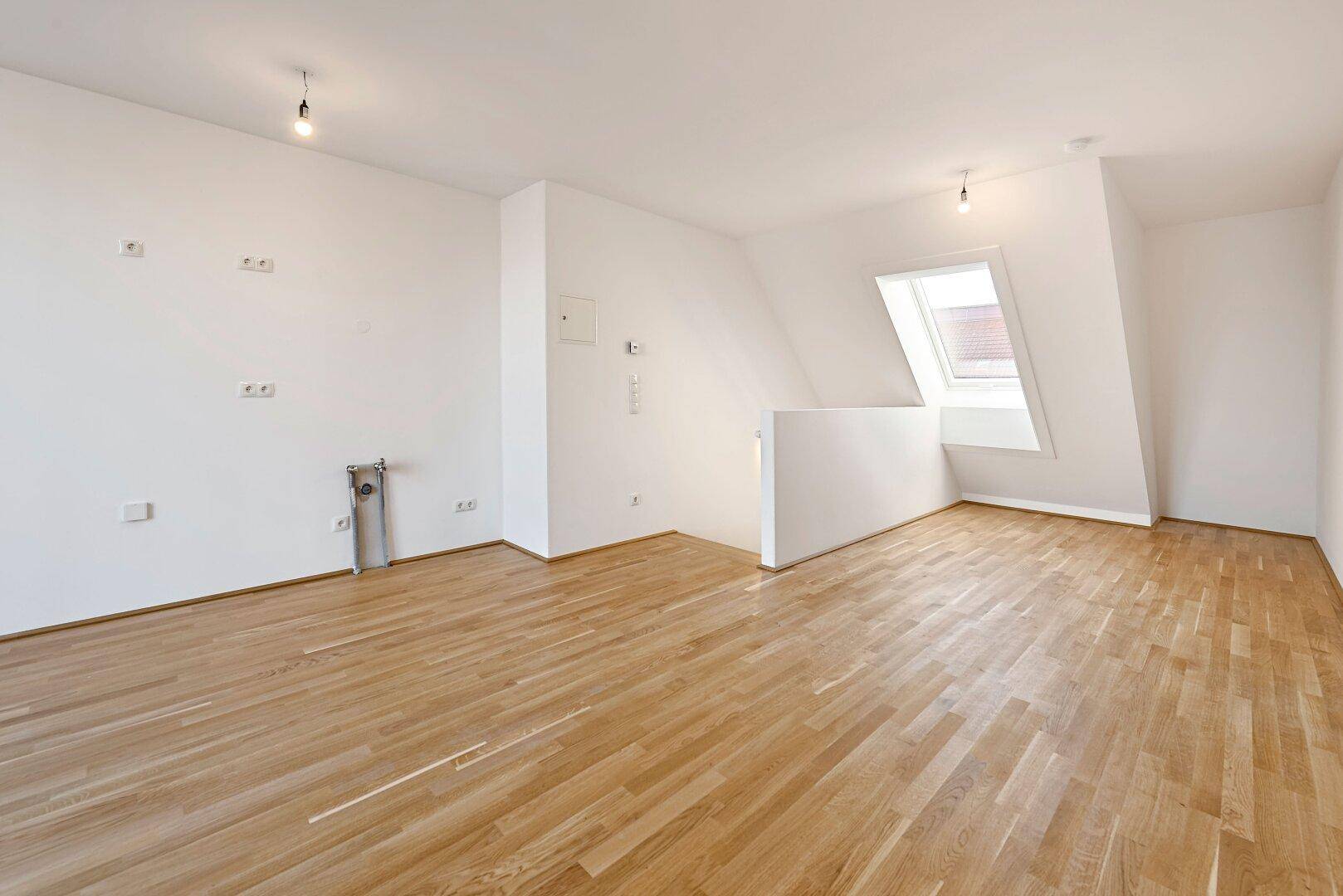 Heller Raum im Dachgeschoss mit Holzboden und Dachfenster, bereit zur individuellen Gestaltung.
