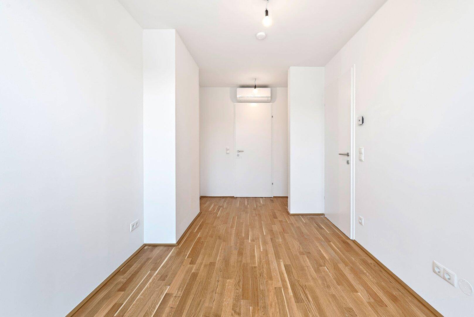 Geräumiger Raum im Dachgeschoss mit Holzboden und Klimaanlage, bereit zur individuellen Einrichtung.