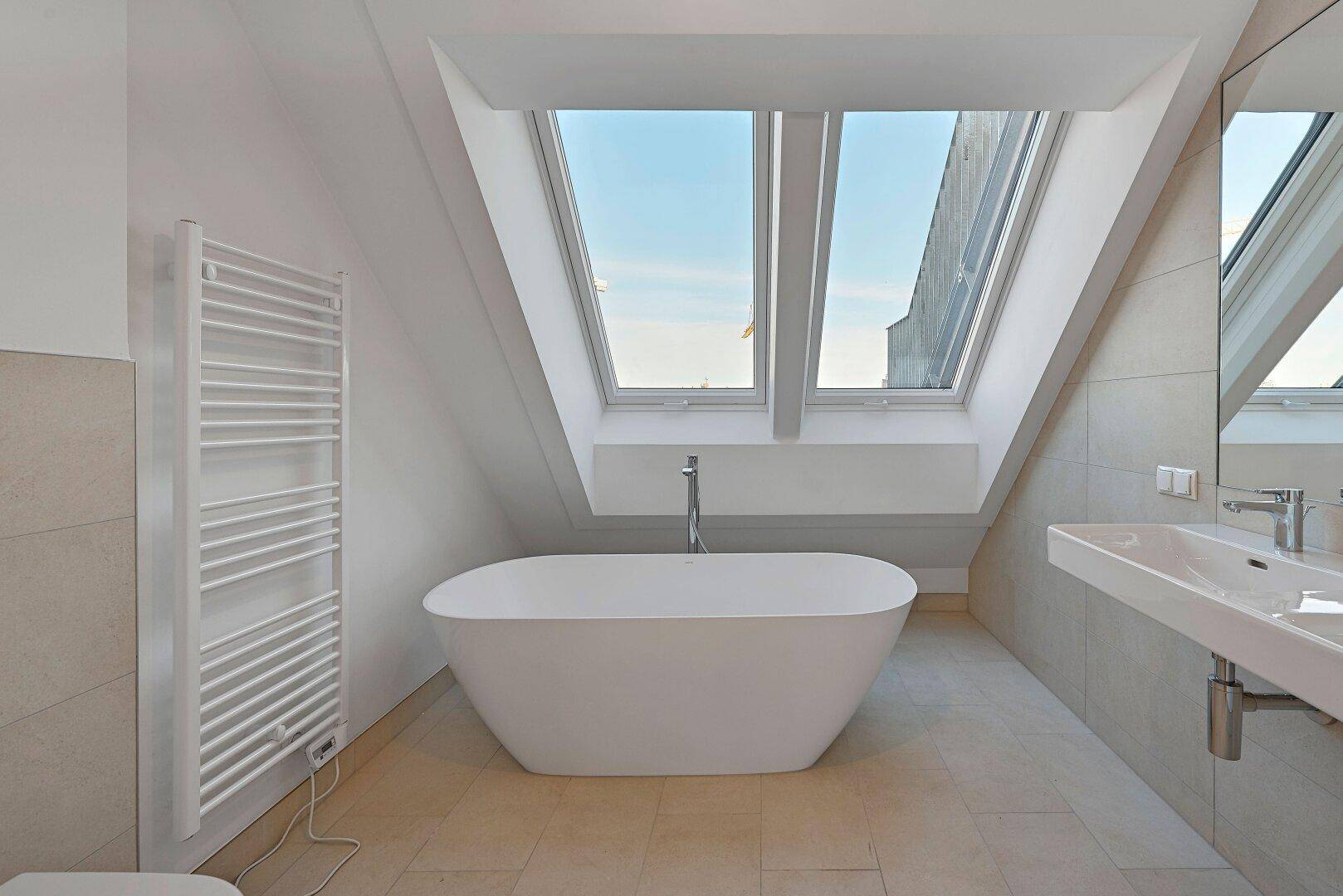 Modernes Badezimmer im Dachgeschoss mit freistehender Badewanne und großen Dachfenstern.