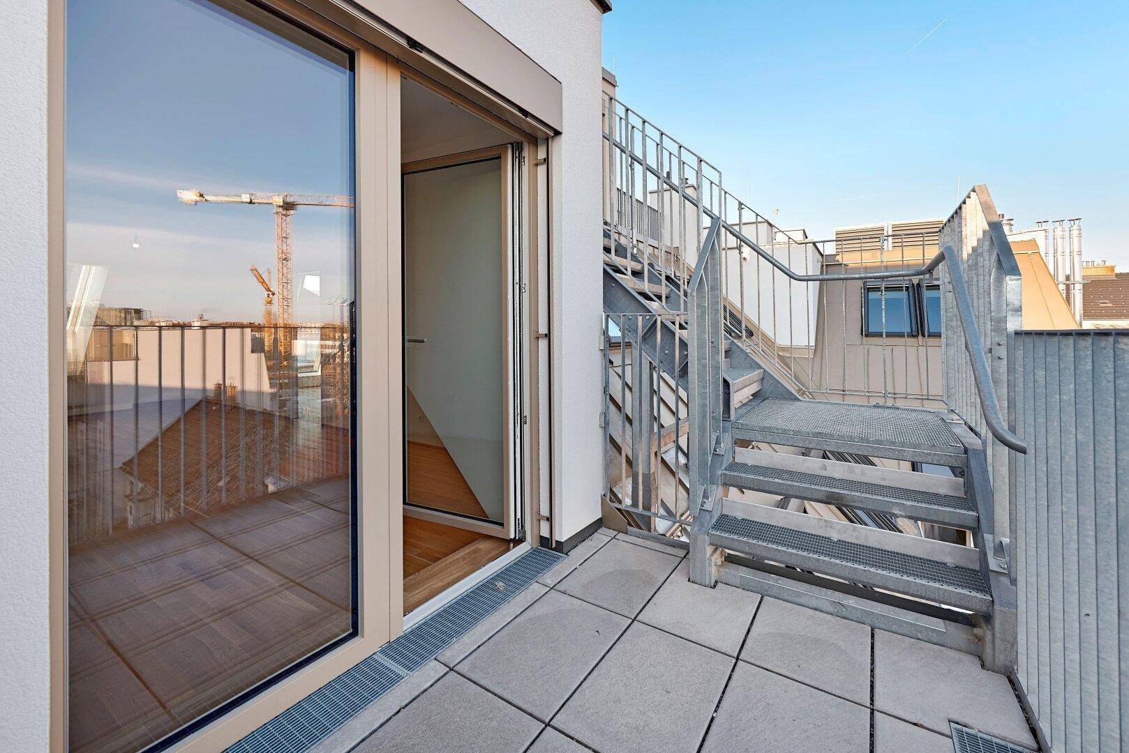 Dachterrasse mit Metalltreppe und Blick auf die Stadt, ideal für entspannte Stunden im Freien.