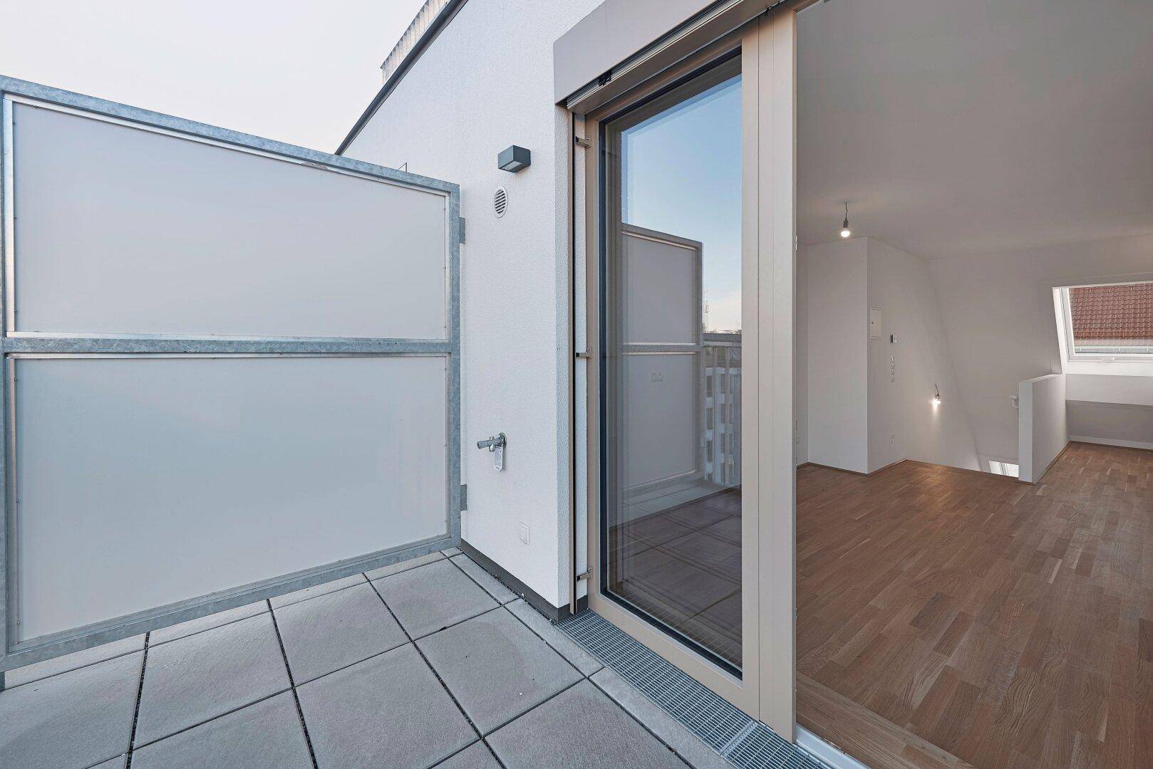 Kleine Terrasse mit Zugang zu einem hellen Innenraum, ideal für frische Luft und Entspannung.