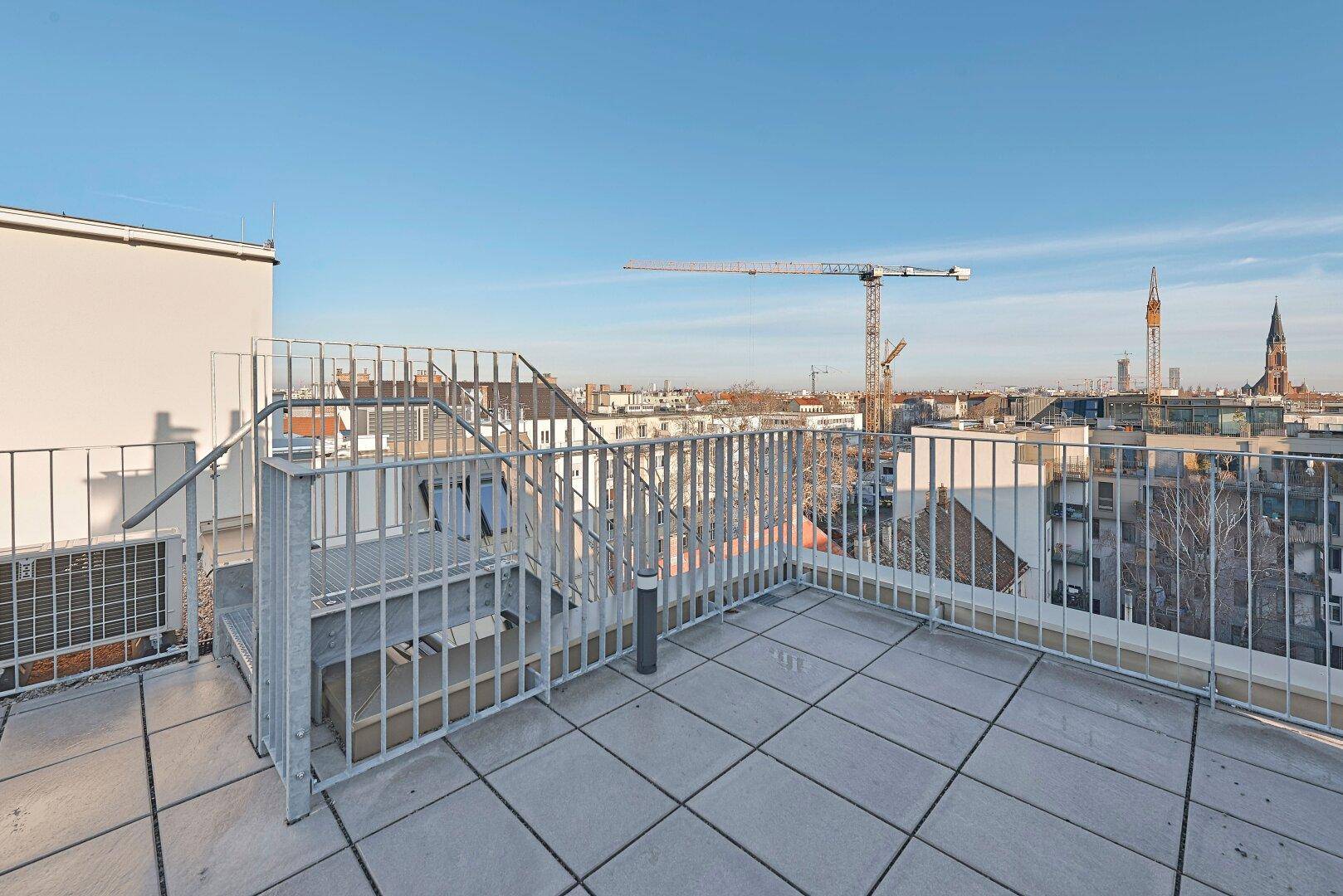 Weitläufige Dachterrasse mit Panoramablick über die Stadt und umliegende Gebäude.