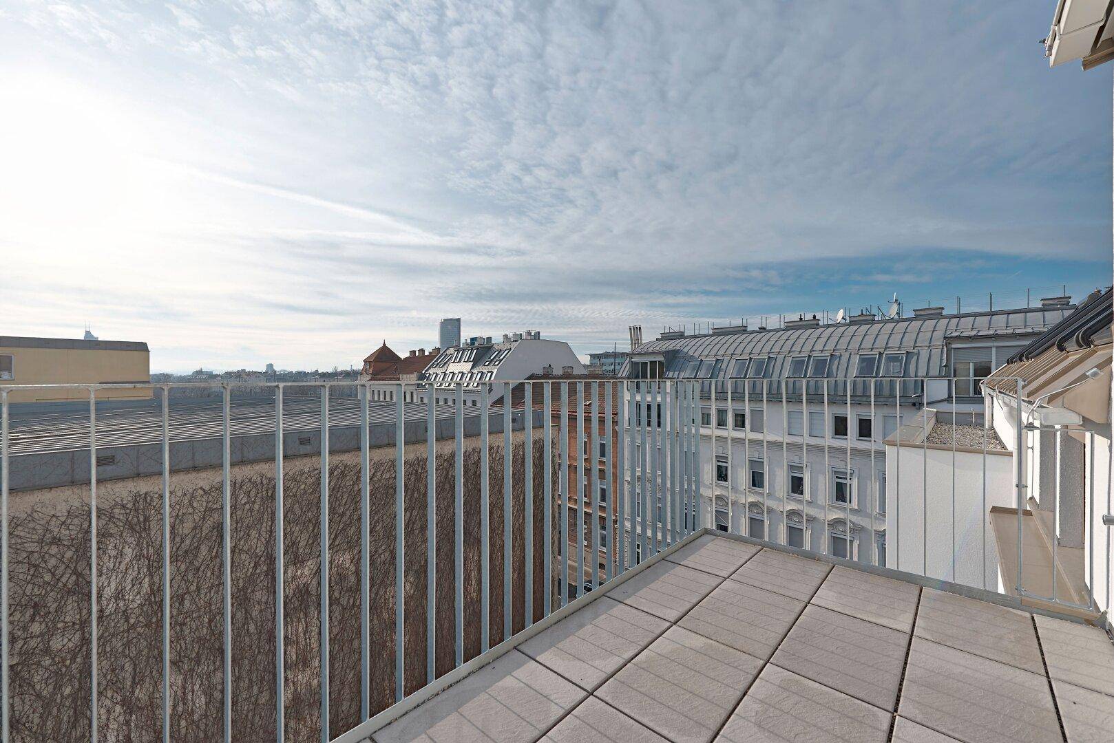Geräumiger Balkon mit Fliesenboden und Metallgeländer bietet einen weiten Stadtblick.