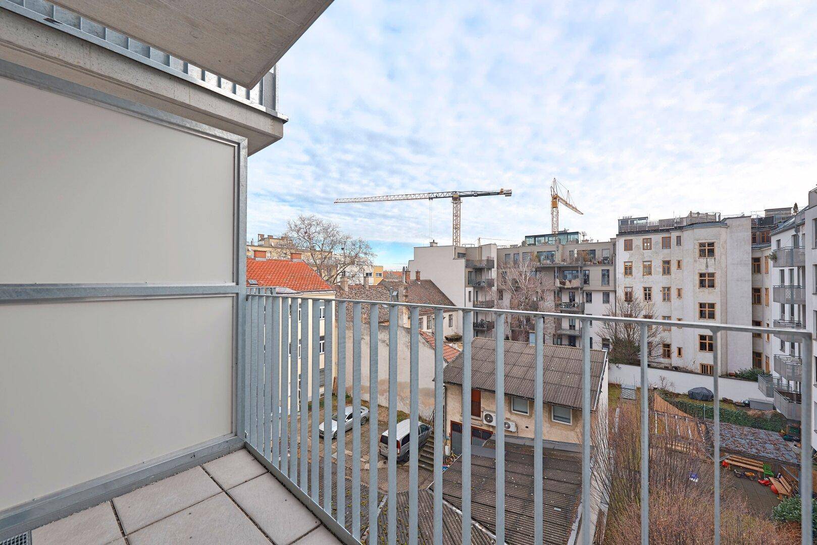 Balkon mit Blick auf die Stadt und umliegende Gebäude, inklusive Baukran im Hintergrund.