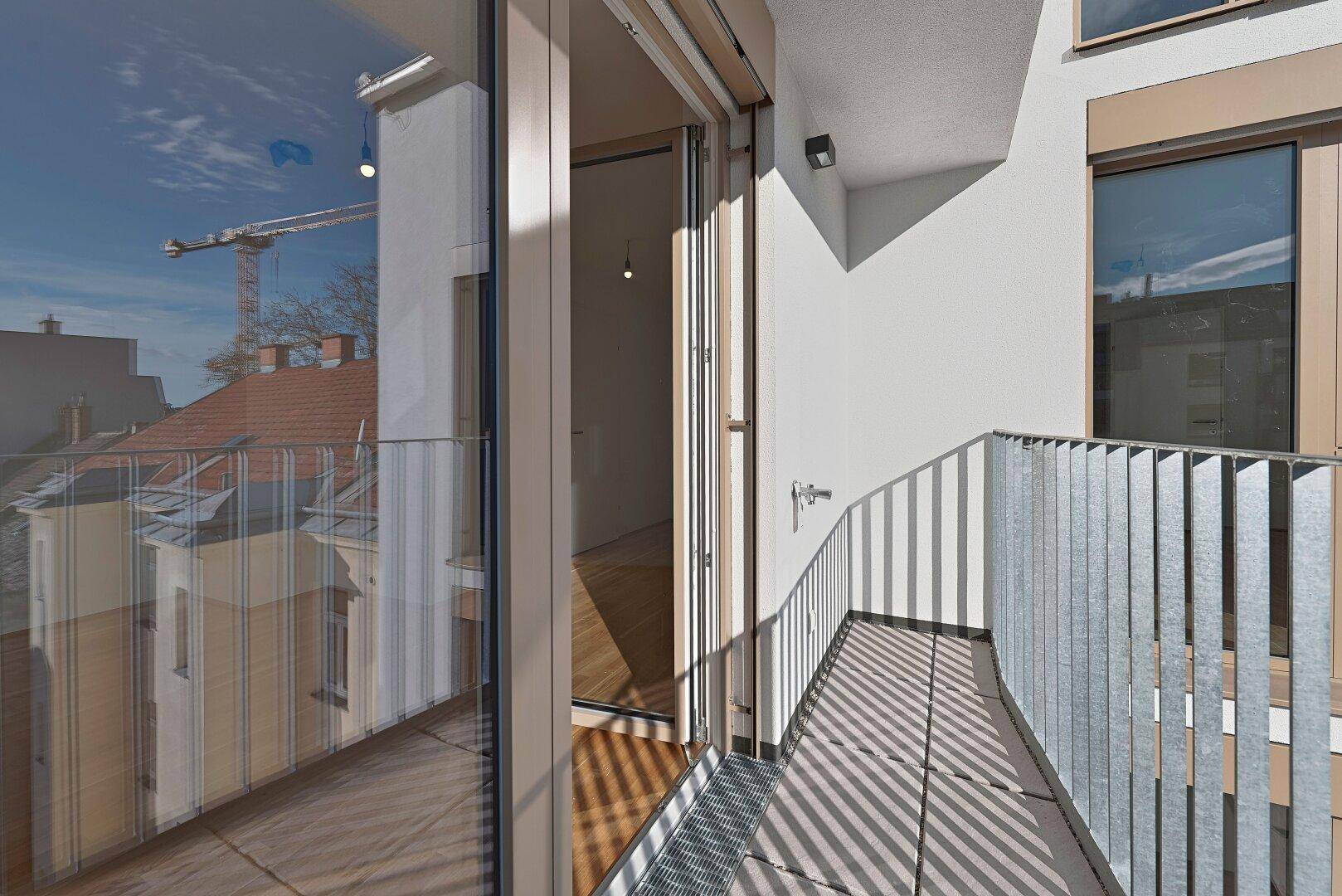 Balkon mit Fliesenboden und Metallgeländer, bietet einen Blick auf die umliegende Stadtbebauung.