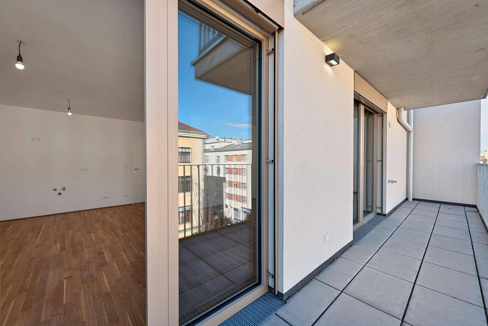Geräumiger Balkon mit Fliesenboden und Zugang zum Innenraum, bietet einen weiten Stadtblick.