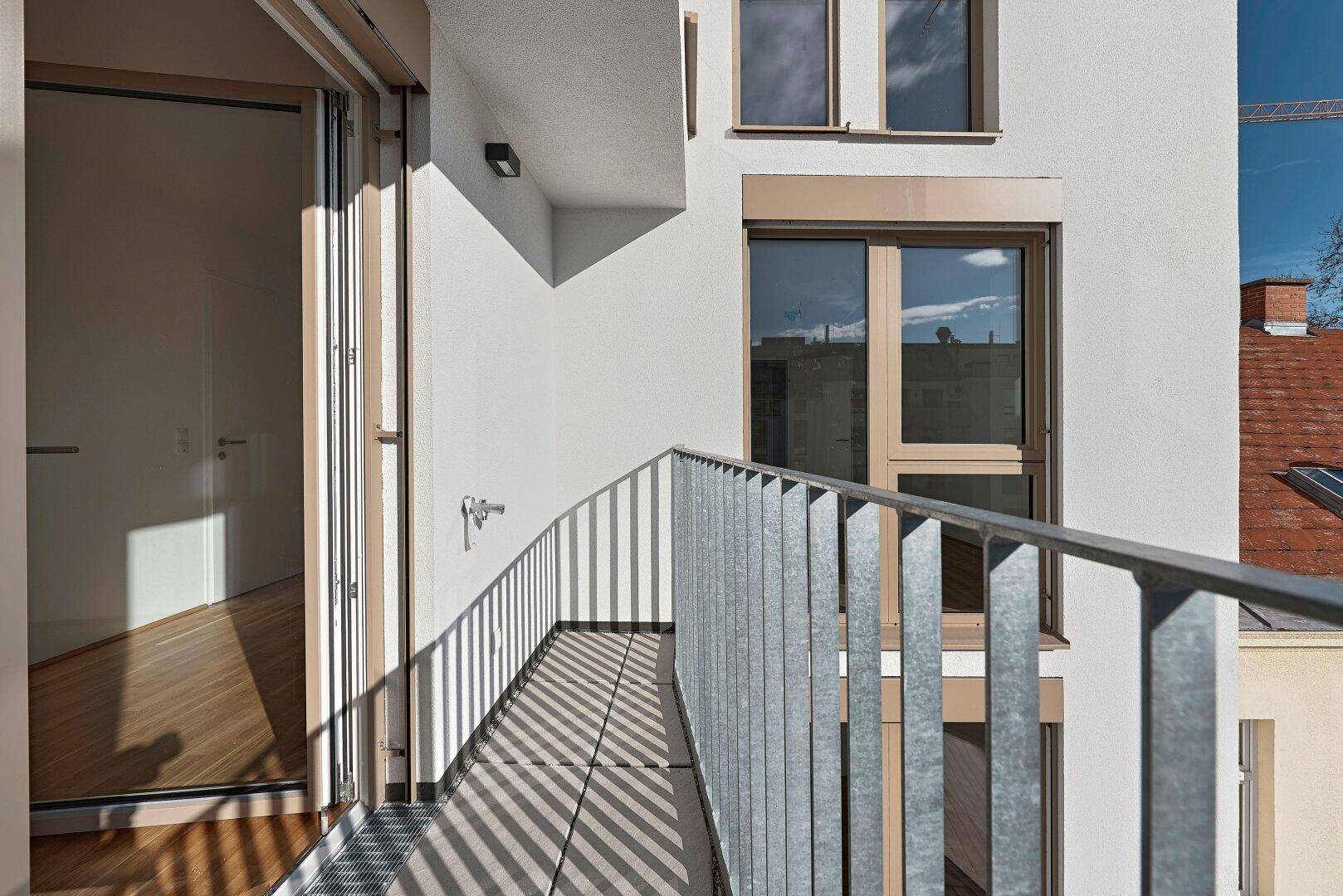 Schmaler Balkon mit modernem Metallgeländer und Blick auf die umliegenden Gebäude.