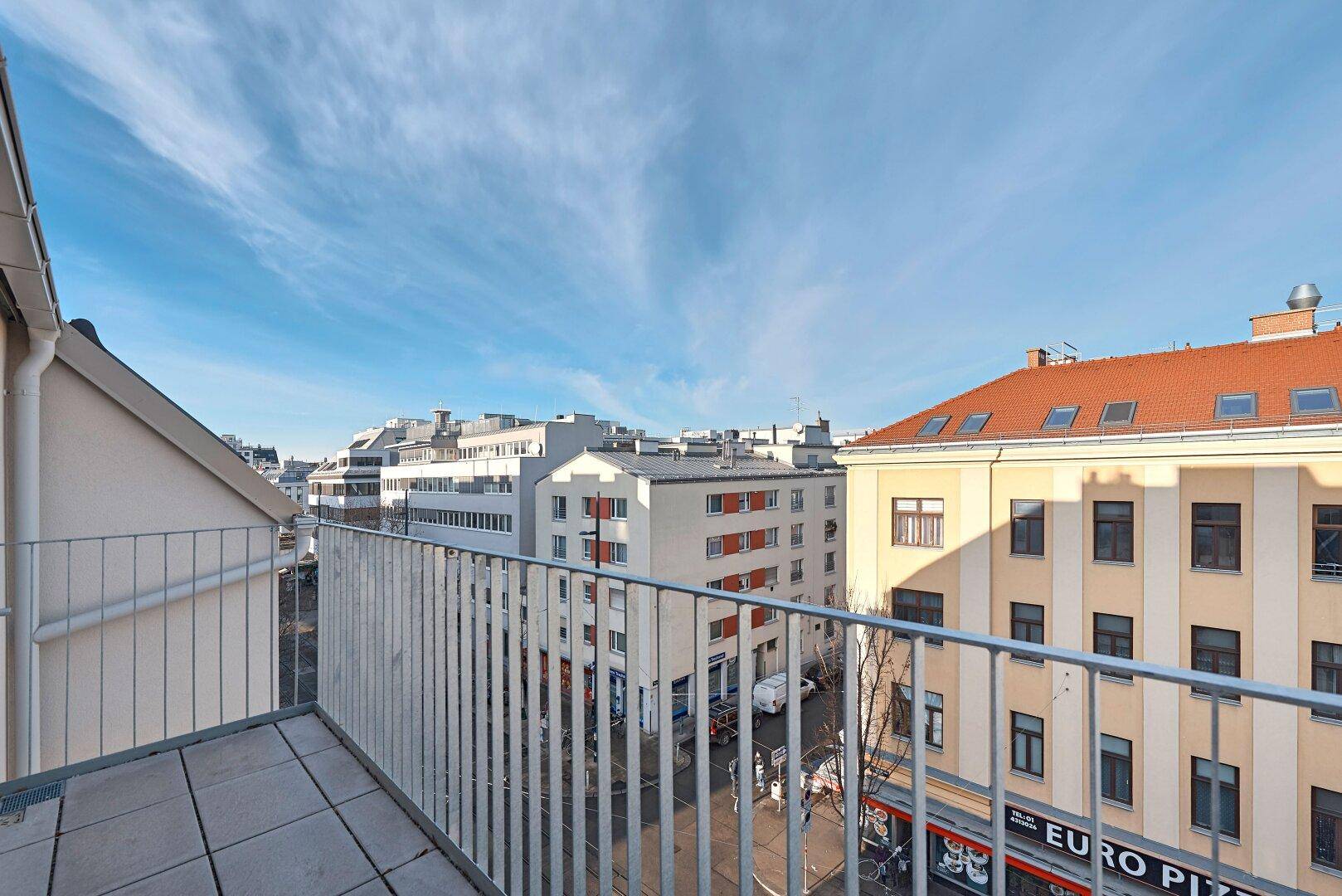 Geräumiger Balkon mit Fliesenboden und weitem Blick über die Dächer der Stadt.
