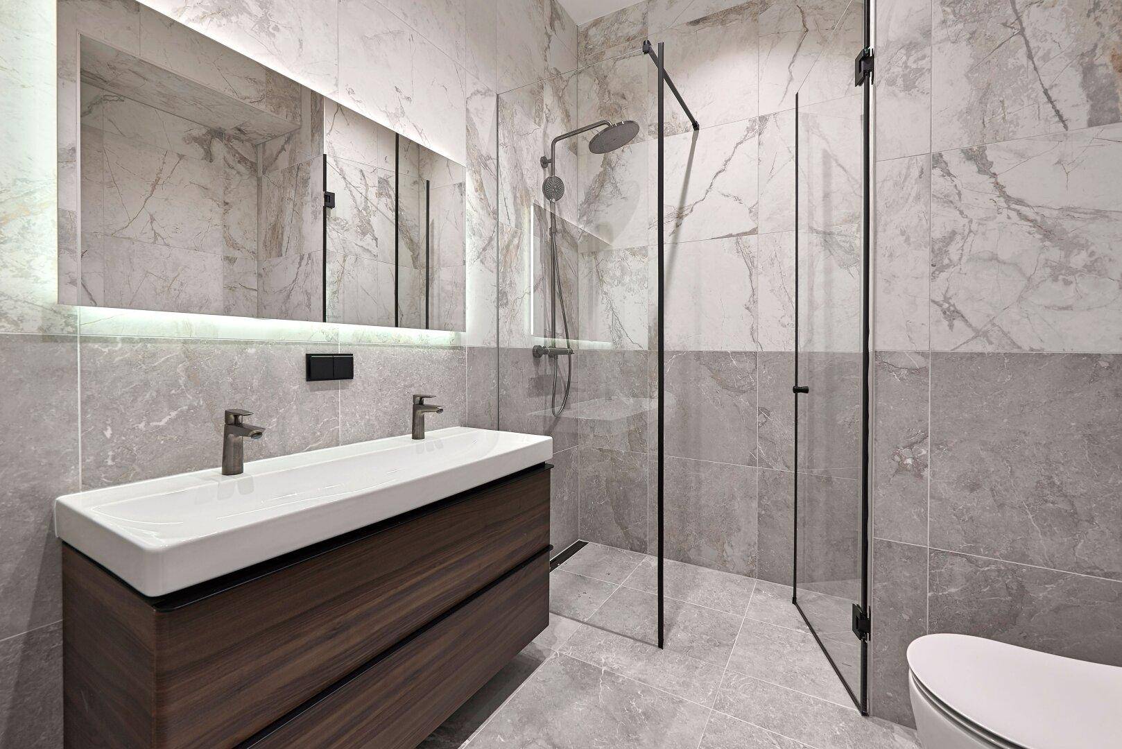 Modernes Badezimmer mit doppelter Waschtischplatte, großer begehbarer Dusche und eleganten Marmorfliesen.