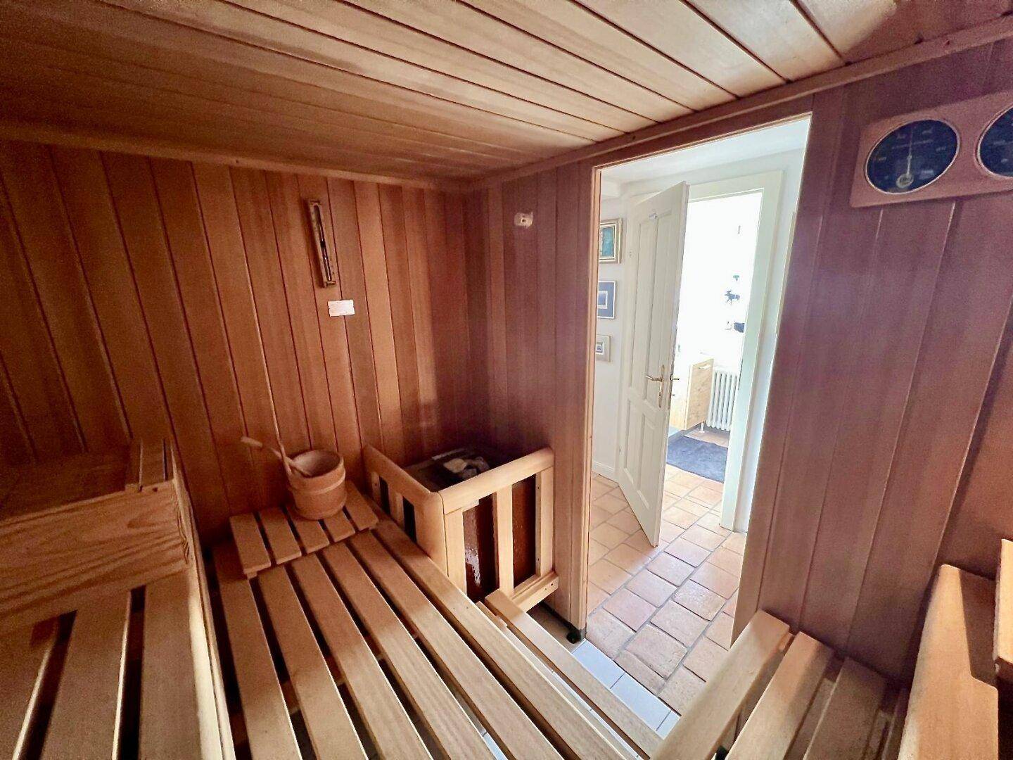 Gemütliche Holzsauna mit Bänken und Saunaofen, ideal zur Entspannung nach einem langen Tag.