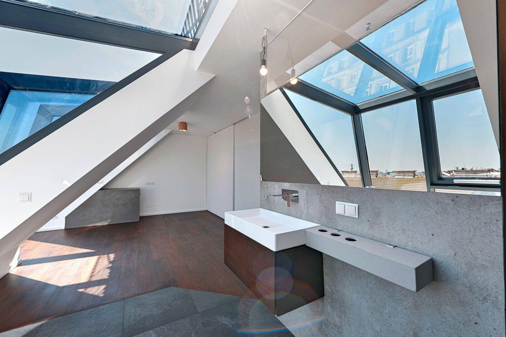 Elegantes Badezimmer mit modernem Waschtisch, großem Spiegel und viel Tageslicht durch Glasflächen.
