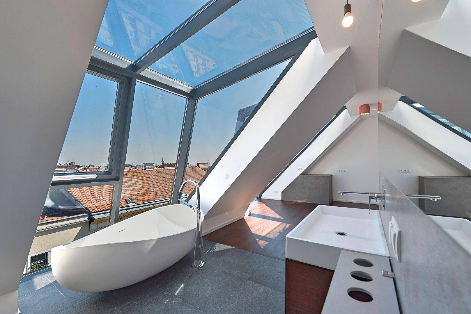 Luxuriöses Badezimmer mit freistehender Badewanne, modernem Waschtisch und beeindruckendem Stadtblick.